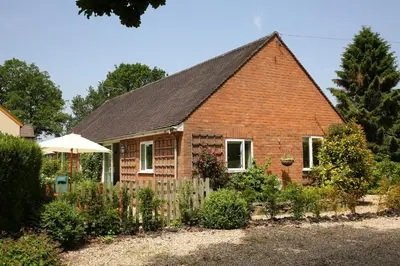 a brick house with a fence in a garden at Pheasant Walk at Eaton Manor in Church Stretton