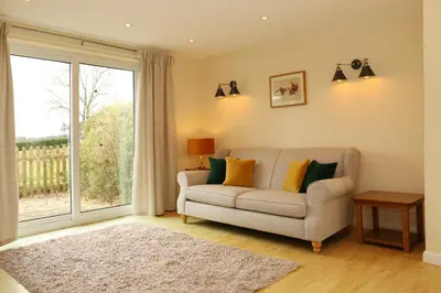 a living room with a couch and a large window at Pheasant Walk at Eaton Manor in Church Stretton