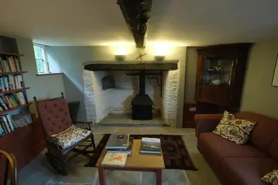 a living room with a fireplace and a couch and a table at Chestnut Cottage in Eardisley