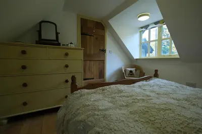 a bedroom with a bed and a dresser and a window at Chestnut Cottage in Eardisley