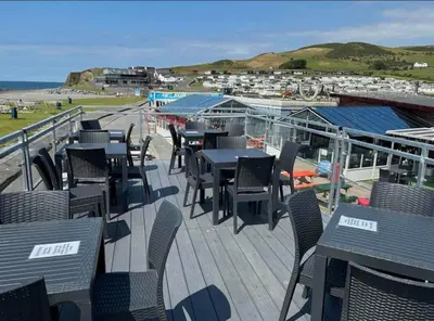 a deck with tables and chairs and the ocean at Sea retreat caravans in Aberystwyth
