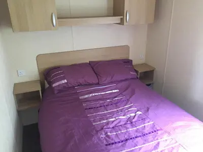 a bed with purple sheets in a small room at Sea retreat caravans in Aberystwyth