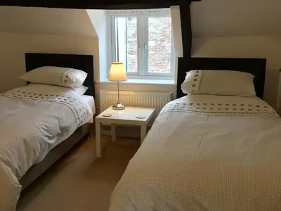two beds in a bedroom with a lamp and a window at March Cottage Brecon in Brecon