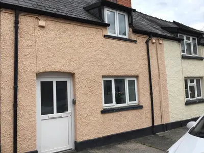a brick house with a white door and two windows at March Cottage Brecon in Brecon