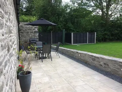 a patio with an umbrella and a table and chairs at The Bakery in Llanddeiniol