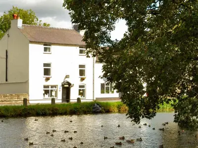 a house with ducks in the water in front of it at Fitzwarine House Whittington in Whittington