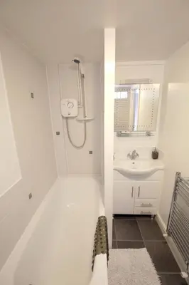 a white bathroom with a shower and a sink at Fitzwarine House Whittington in Whittington