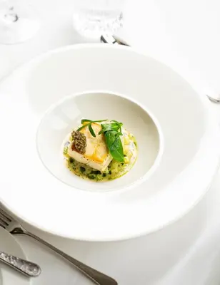 a white plate with a dish of food on a table at Palé Hall in Bala