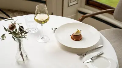 a table with a plate of food and a glass of wine at Palé Hall in Bala