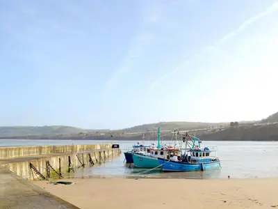 a blue boat is docked next to a pier at Seascape in New Quay