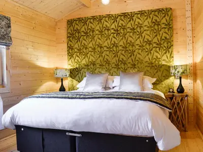 a bedroom with a large bed in a wooden wall at Ty Pren in Dyffryn