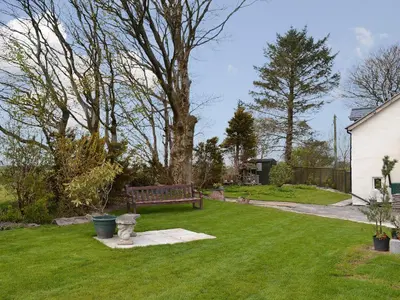 a park bench sitting in the grass next to a house at Bryntrisant in Devils Bridge