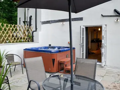 an outdoor hot tub with a glass table and an umbrella at Bryn Aled in Llanfachreth