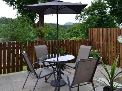 a table and chairs with an umbrella on a patio at Bryn Aled in Llanfachreth