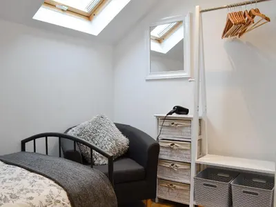 a bedroom with a bed and a chair and windows at Bryn Aled in Llanfachreth