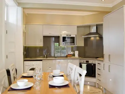 a kitchen with a wooden table and white cabinets at Llys yr Wylan in Aberystwyth
