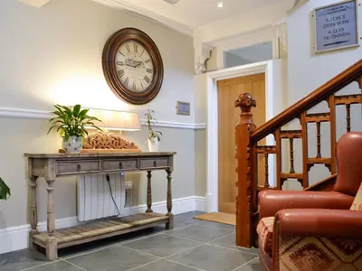 a living room with a clock on the wall and a table at Llys yr Wylan in Aberystwyth