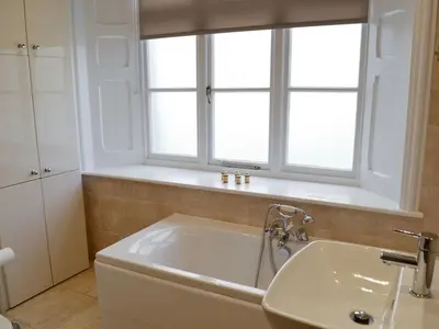 a white bathroom with a sink and a window at Llys yr Wylan in Aberystwyth