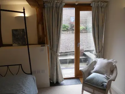 a bedroom with a bed and a chair and a window at The Barn at Titley in Kington