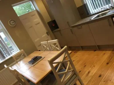 a kitchen with a wooden table with two chairs and a sink at Llys y Dderwen - Oak Court in Aberystwyth