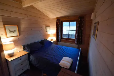 a bedroom with a bed and a desk and a window at Log Cabin in Brecon