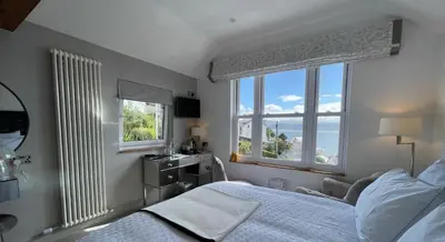 a bedroom with a bed and two windows at Brig-y-Don in Aberdyfi