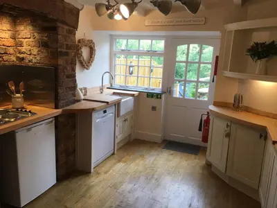 a kitchen with white cabinets and a brick wall at Riverside Suites Llangollen in Llangollen