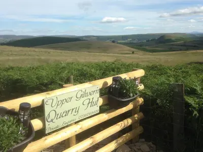 a sign on a wooden fence with plants on it at Upper Gilwern Quarry Hut in Llandrindod Wells