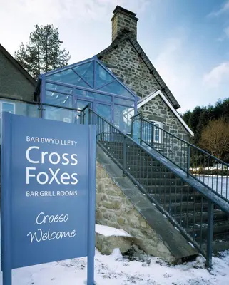 a sign in front of a building with a house at Cross Foxes - Bar Grill Rooms in Dolgellau
