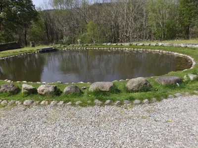 a pond with rocks in the middle of a park at cosy ground floor disabled friendly room in farm house in Bala