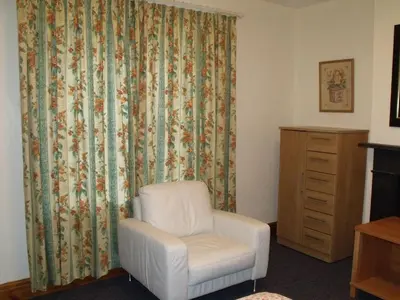 a room with a white chair and a dresser at cosy ground floor disabled friendly room in farm house in Bala