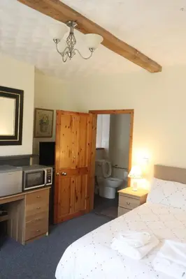 a bedroom with a bed and a bathroom with a toilet at cosy ground floor disabled friendly room in farm house in Bala