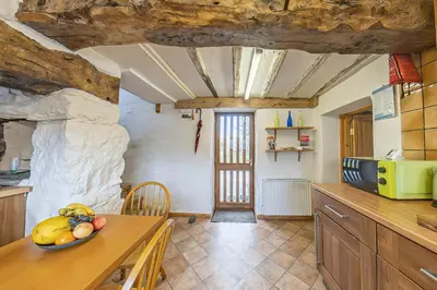 a kitchen with a table with a bowl of fruit on it at Beautiful 16th Century Ty Cerrig Cottage, set in stunning grounds with great views in Corwen