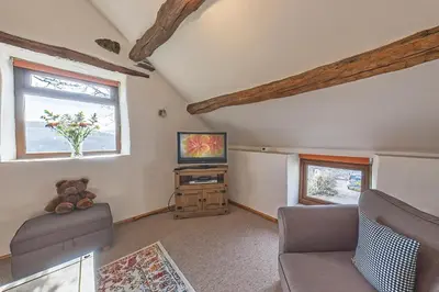 a living room with a couch and a television at Beautiful 16th Century Ty Cerrig Cottage, set in stunning grounds with great views in Corwen