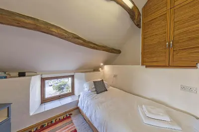 a small bedroom with a bed and a window at Beautiful 16th Century Ty Cerrig Cottage, set in stunning grounds with great views in Corwen