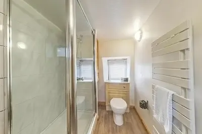 a white bathroom with a shower and a toilet at Beautiful 16th Century Ty Cerrig Cottage, set in stunning grounds with great views in Corwen