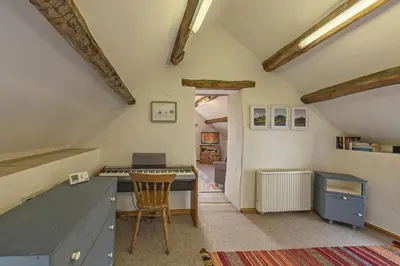 an attic kitchen with a desk and a table at Beautiful 16th Century Ty Cerrig Cottage, set in stunning grounds with great views in Corwen