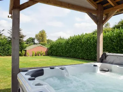 a hot tub under a pergola in a yard at River Cottage in Llangunllo