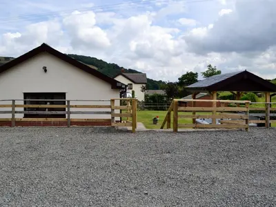 a wooden fence in front of a white building at River Cottage in Llangunllo