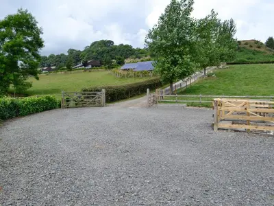 a gravel road with a fence and a field at River Cottage in Llangunllo