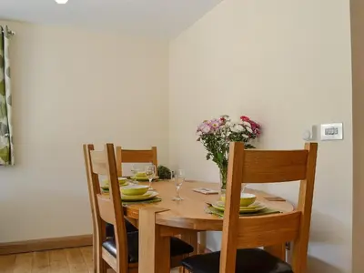 a wooden table with chairs and a vase of flowers at River Cottage in Llangunllo