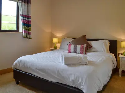 a bedroom with a bed with white sheets and pillows at River Cottage in Llangunllo