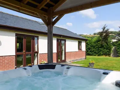 a hot tub in the backyard of a house at River Cottage in Llangunllo