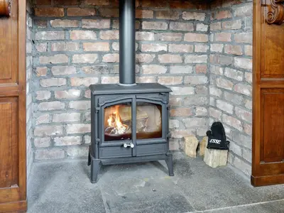 a brick fireplace with a fire in it at Yr Hen Fanc in Trawsfynydd