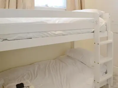 two white bunk beds in a room with a bed at Yr Hen Fanc in Trawsfynydd