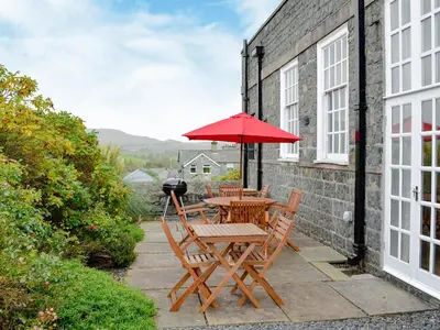 a table and chairs with a red umbrella on a patio at Yr Hen Fanc in Trawsfynydd