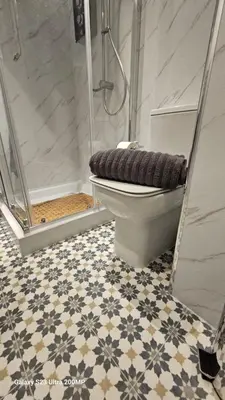 a bathroom with a toilet and a shower with a tile floor at Bala Holiday Suites in Bala