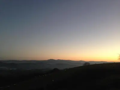 a sunset on a hill with mountains in the background at Owl Barn at Penygaer Great views of Brecon Beacons in Llandovery