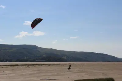 a man flying a kite on a beach at Yr Hen Feudy in Barmouth