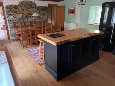 a kitchen with a wooden island in a room with a table at Yr Hen Feudy in Barmouth